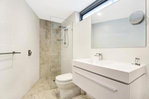 Beachfront Cabarita Apartment by Kingscliff Accommodation في كاباريتا بيتش: حمام مع حوض ومرحاض ومرآة