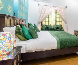 a bedroom with a large bed with green pillows at Hotel Heritage House in Jaisalmer