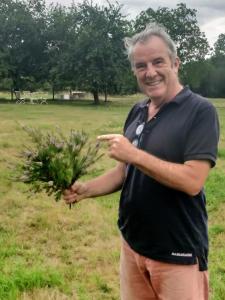 a man holding a plant in a field at La Petite Bruyere De Renaix in Ronse