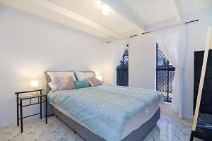 a white bedroom with a bed and a window at Caba Shack by Kingscliff Accommodation in Cabarita Beach