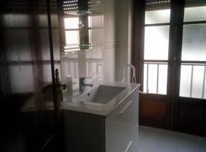 a white bathroom with a sink and a window at Lá em Cima in Sesimbra