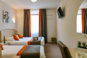 a hotel room with two beds and a table at Hôtel Le Kolibri in Tournus