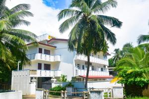 a building with palm trees in front of it at Di Sicuro Tourist Inn in Hikkaduwa