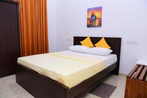 a bedroom with a large bed with yellow pillows at Airport Blessings Villa in Katunayaka