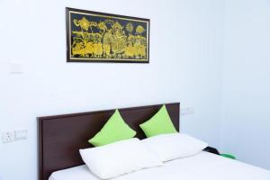 um quarto com uma cama com almofadas verdes e brancas em Airport Blessings Villa em Katunayaka
