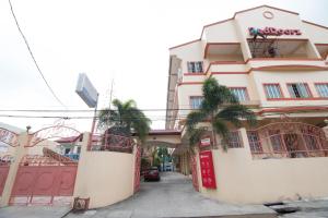 un bâtiment rose avec des palmiers devant lui dans l'établissement RedDoorz Praferosa Resort Hotel Calamba, à Calamba