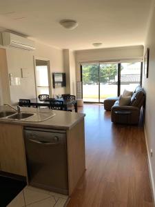 ein Wohnzimmer mit einer Küche und ein Wohnzimmer mit einem Sofa in der Unterkunft Holdfast Shores Apartments in Adelaide