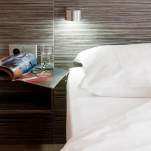 a bed with a book and a drink on a night stand next to a bed at Appartementen Hotel Geuldal in Epen