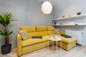 - un canapé jaune dans le salon avec une table dans l'établissement Apartments Front Park Sadowa by Renters, à Gdańsk