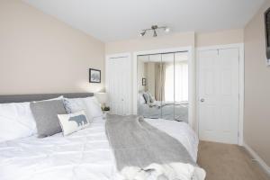 1 dormitorio con cama blanca y espejo en Mountain Base Retreat @ The Gables en Whistler