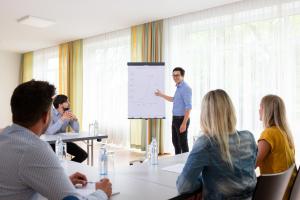 a man giving a presentation to a group of people in a meeting at campus Horn in Horn