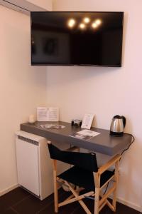 a desk with a television on a wall with a chair at Locanda Dolcevita in Dozza