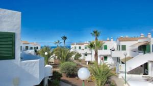- une vue sur une maison avec des palmiers et l'océan dans l'établissement Kiwi Smoothie - En la playa, doble terraza, cocina completa, dos camas y Wifi, à El Cotillo