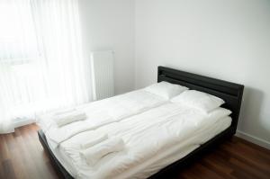 a bed with white sheets and pillows in a bedroom at Apartament Rosso in Łódź