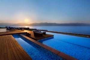 a swimming pool with the sun setting over the water at Herbert Samuel Royal Shangri-La Eilat in Eilat