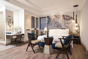 a bedroom with a bed and a desk and a table at Sofiana My Khe Hotel & Spa- Rooftop Pool Bar in Danang