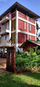 een rood-wit gebouw met een bakstenen pilaar ervoor bij Oasis Resort in Diveagar