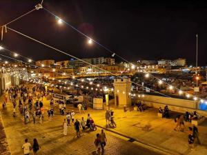 un grupo de personas caminando por una ciudad por la noche en Agorà Bisceglie, en Bisceglie