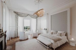 a white bedroom with a bed and a large window at La Villa Guy & Spa - Teritoria in Béziers