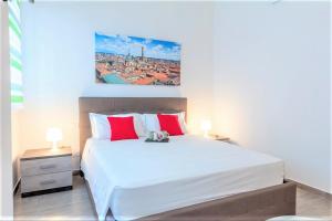 um quarto com uma grande cama branca com almofadas vermelhas em Realkasa Azzarita Flat em Bolonha