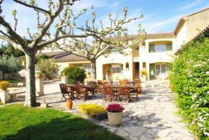 a patio with tables and chairs in front of a house at Le Mas de l'Amandier in Saint-Saturnin-lès-Avignon