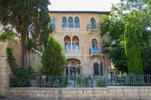 a brick building with a fence in front of it at Villa Brown Moshava - a member of Brown Hotels in Jerusalem