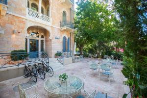 eine Terrasse mit Tischen und Stühlen und ein Gebäude in der Unterkunft Villa Brown Moshava - a member of Brown Hotels in Jerusalem