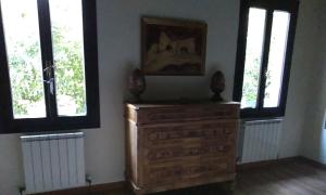 un comò in legno in una stanza con due finestre di Ca' del Tajo a Teglio Veneto