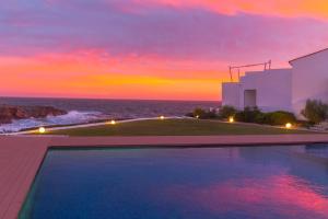 a swimming pool with a sunset in the background at BINIPARADISE - Villa Excellent in Binibeca