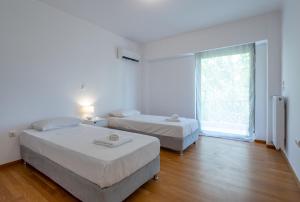 two beds in a white room with a window at Hippocrates - Faliro deluxe apartment in Athens