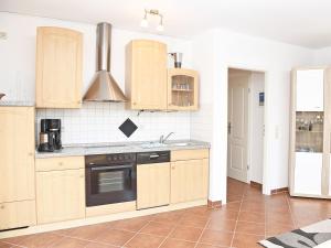 Una cocina con gabinetes de madera y un horno de estufa. en Ferienwohnung Ostseebrise, en Thiessow