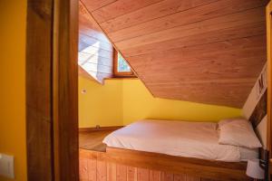 a bed in a room with a wooden ceiling at The Dragon Barn - Grenier in Ascou