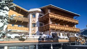 un gran edificio con balcones de madera y nieve. en Hotel Donnerhof, en Fulpmes