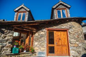 een stenen huis met een houten deur en ramen bij The Dragon Barn - Grenier in Ascou