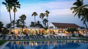 a resort with a pool and chairs and palm trees at Sunbeach Hotel & Resort in Bakau