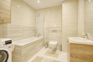 een badkamer met een bad, een toilet en een wastafel bij Valensia Apartment in Druskininkai +12 foto's