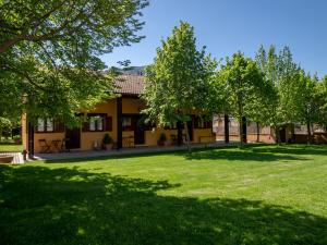 una casa con un patio con césped verde y árboles en La Estibialla, en Campo