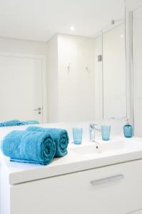 un bagno bianco con asciugamani blu su un lavandino di Luxury villa & private heatable pool in Albufeira ad Albufeira Altre 34 foto