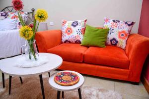 uma sala de estar com um sofá laranja e uma mesa em West Suites Sherry Homes em Nairobi