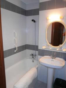 y baño con lavabo, bañera y espejo. en Hostal La Tablada, en Navaleno