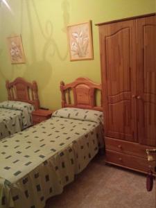 a bedroom with two beds and a cabinet at Hostal Vaticano in Alfajarín