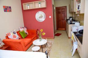 sala de estar con sofá naranja y mesa en West Suites Sherry Homes en Nairobi