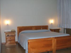 1 dormitorio con 1 cama de madera y 2 mesitas de noche en Hotel Ristorante Da Gianni, en Bovolone