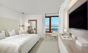 a white bedroom with a large bed and a flat screen tv at Hotel Victoria Gran Meliá in Palma de Mallorca