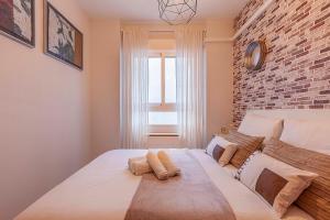 sypialnia z dużym białym łóżkiem z ceglaną ścianą w obiekcie Apartamento Gran Via Center w Grenadzie