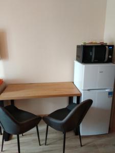 kuchnia ze stołem, 2 krzesłami i kuchenką mikrofalową w obiekcie Apartmán ALEX w Popradzie