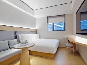 Schlafzimmer mit einem Bett, einem Tisch und einem TV in der Unterkunft Ji Hotel Orchard Singapore in Singapur