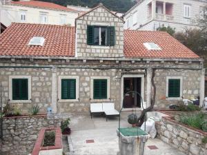 una vieja casa de piedra con persianas verdes. en Apartment Dubrava, en Dubrovnik