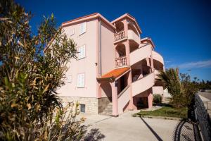 a pink building with a balcony on the side at Pink House Apartments in Novalja