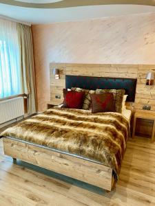 Schlafzimmer mit einem großen Bett mit einem Kopfteil aus Holz in der Unterkunft Boutique Hotel Goldene Henne in Wolfsburg